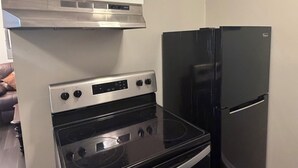 A kitchen with a stainless steel oven, a black refrigerator, and white cabinets.