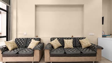 Two sofas with patterned upholstery and matching cushions, positioned in a room with a plain wall and a window to the left.