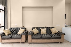 Two sofas with patterned upholstery and matching cushions, positioned in a room with a plain wall and a window to the left.