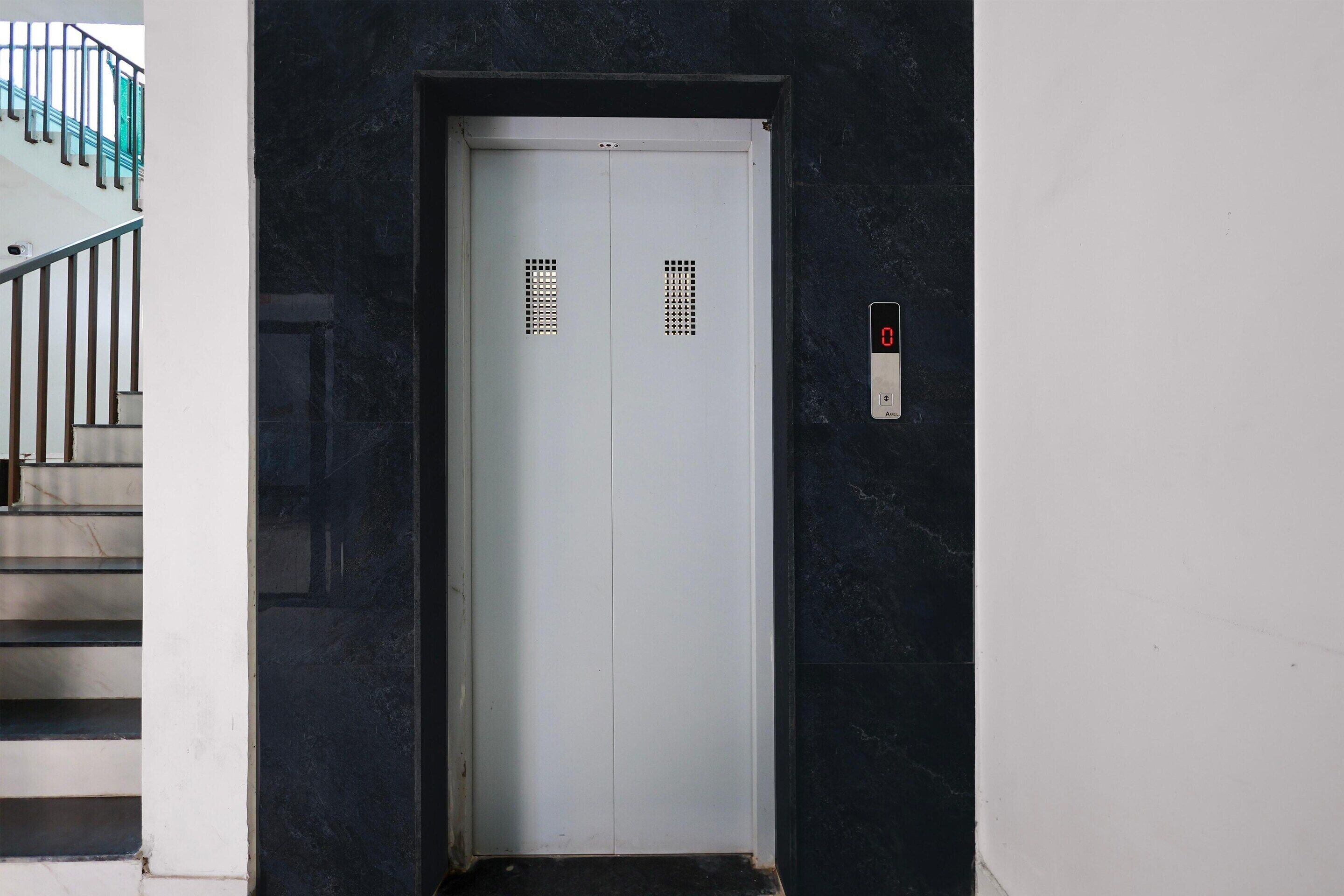 A closed elevator door with a digital display and a keypad on the wall.