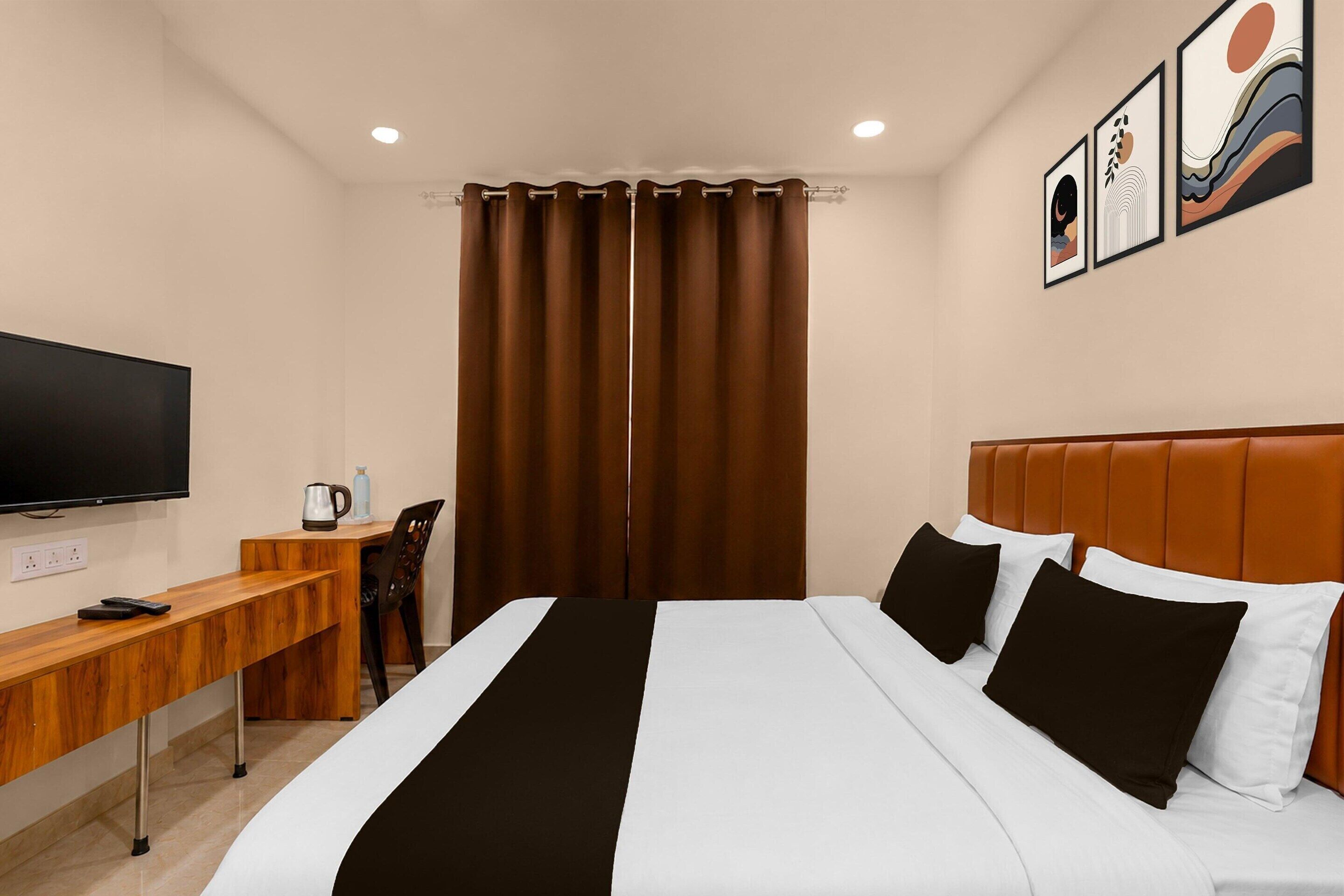 A hotel room with a bed, a desk, a chair, a television, and a window with curtains.