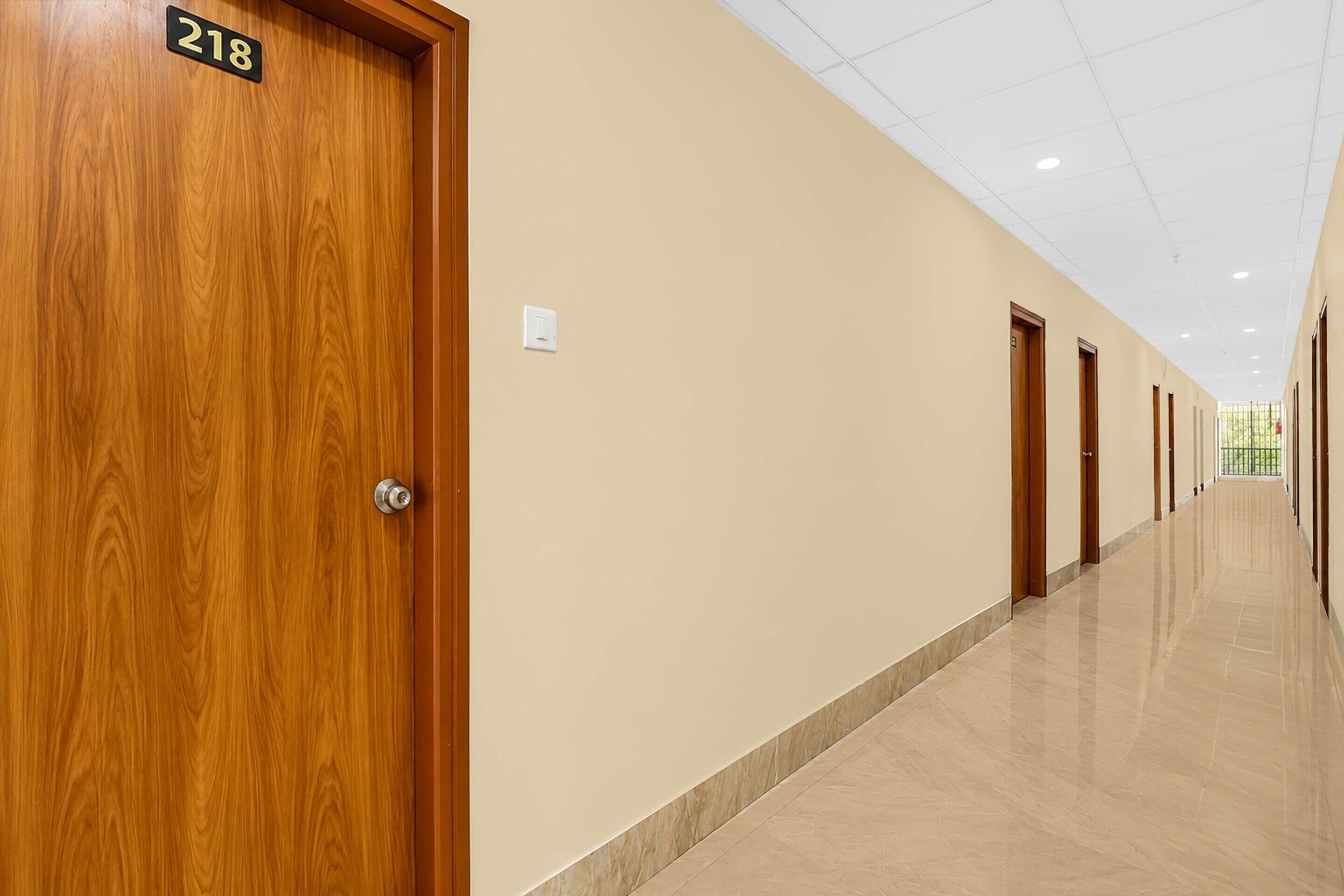 A hotel corridor with wooden doors, numbered 218, and a tiled floor.