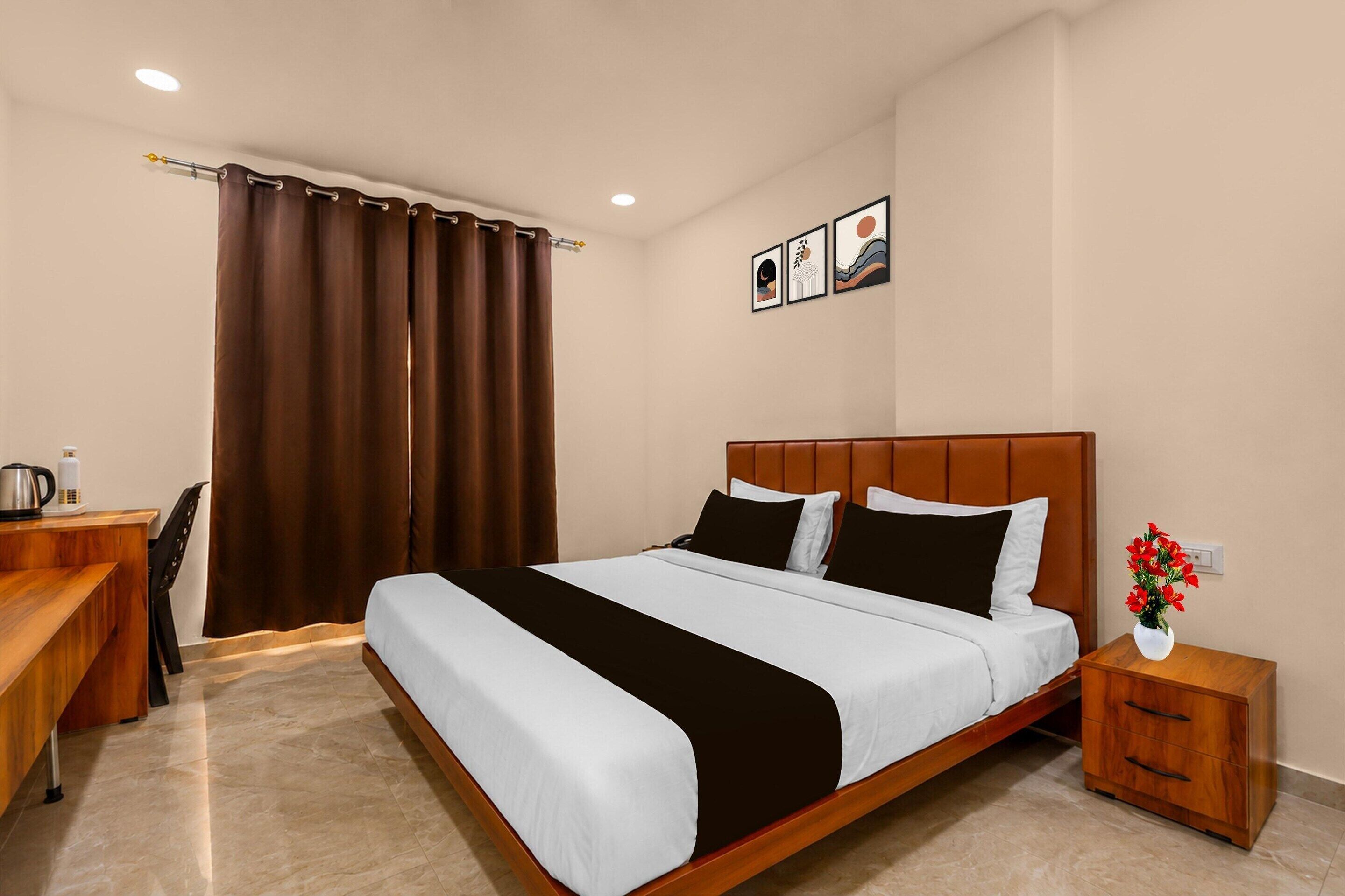 A hotel room with a bed, bedside table, and a desk with a chair.