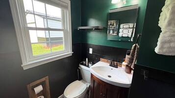 A bathroom with a toilet, sink, and mirror.