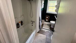 Een badkamer met bad, douche, toilet en wastafel.