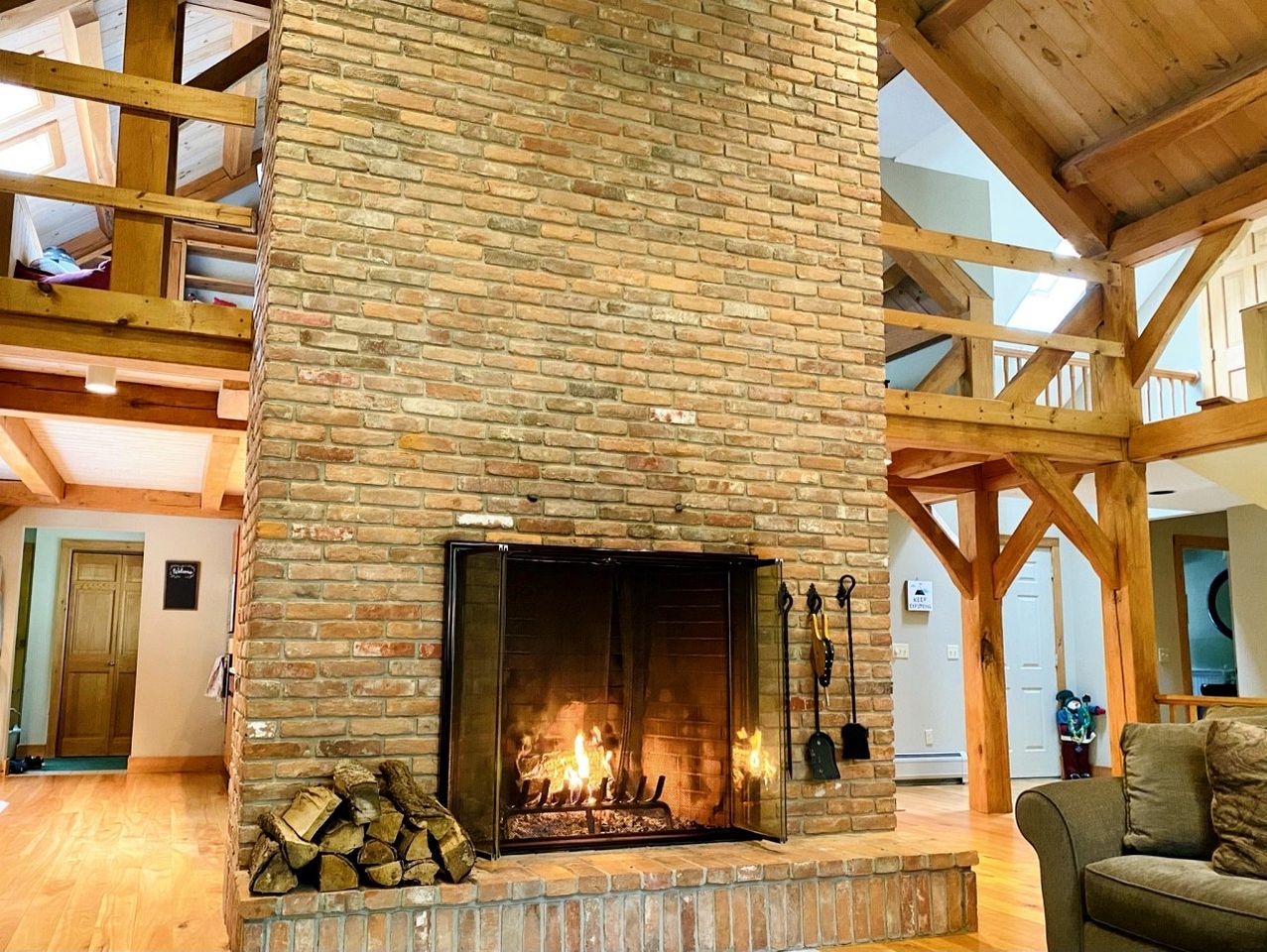 A fireplace with a brick surround, wooden beams, and a visible fire.