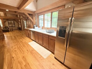 A spacious kitchen with wooden cabinets, a stainless steel refrigerator, and a large window providing natural light. - Mountain Retreat with Stone Fireplace & Game Room Near Stratton, Magic Mountain & Bromley Mountain, Peru, Vermont (Peru)