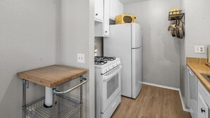 A compact kitchen with a wooden countertop, white cabinets, a gas stove, and a refrigerator. - Lakeside Vibes | 2BR, Walk to Boulder Bay, Pool (Big Bear Lake)