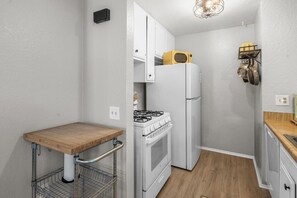 A compact kitchen with a wooden countertop, white cabinets, a gas stove, and a refrigerator. - Lakeside Vibes | 2BR, Walk to Boulder Bay, Pool (Big Bear Lake)