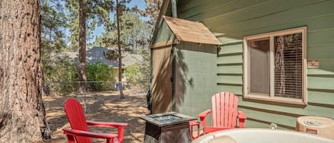 A wooden deck with a hot tub, two Adirondack chairs, and a covered area.