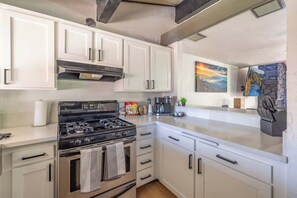 A kitchen with white cabinets, a gas stove, and a coffee maker. - Après All Day | Walk to Summit, Community Hot Tub (Big Bear Lake)
