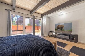 Ein Schlafzimmer mit Bett, Fernseher und einer Schiebetür zu einem Außenbereich.