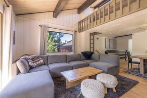 Ein modernes Wohnzimmer mit einem Ecksofa, einem Couchtisch aus Holz und zwei Poufs.