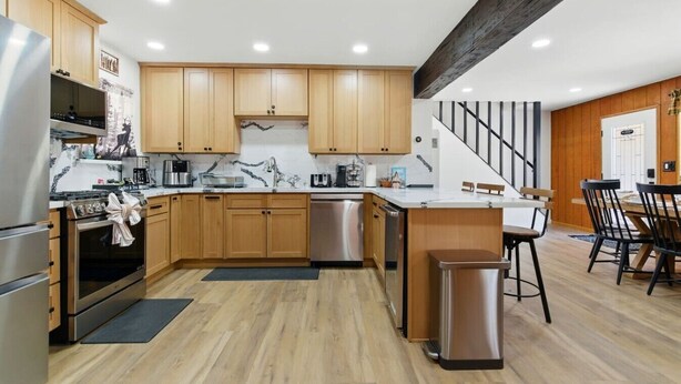 Una cocina moderna con armarios de madera, electrodomésticos de acero inoxidable y una isla central.