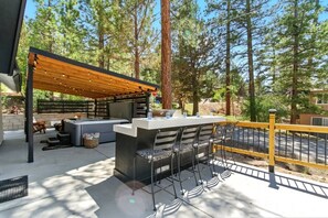 An outdoor patio with a built-in grill, seating area, and a pergola with string lights. - Big Bear Cabana Near Lake W/ Hot Tub, Shuffleboard (Big Bear Lake)