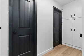 A hallway with two black doors and a set of white cabinets. - Big Bear Cabana Near Lake W/ Hot Tub, Shuffleboard (Big Bear Lake)