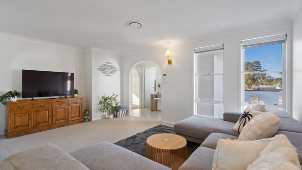 A modern living room with a flat-screen TV, wooden cabinet, grey sofas, and a view of the outside. - 4 Murray Avenue, Forster (Forster)