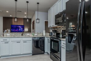 A modern kitchen with a built-in dishwasher, a microwave, and a refrigerator. - 5BR Veranda Palms Home Near Disney for 14 (Kissimmee)