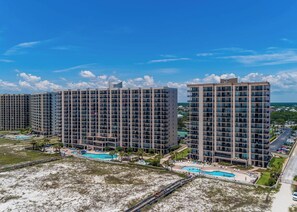 Un hôtel de grande hauteur, avec de nombreux étages, une piscine et une vue sur la plage.