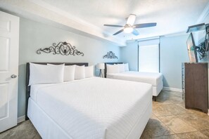A hotel room with two beds, a ceiling fan, a decorative wall piece, and a wooden dresser. - Phoenix East 511 Gulf-Front Corner Condo (Orange Beach)