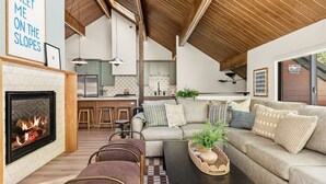 A cozy living room with a fireplace, a sofa set, and a coffee table with a plant. - Slope & Cedar House | Hot tub, Steps 2 Snow Summit (Big Bear Lake)
