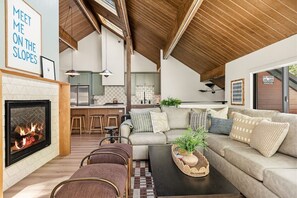 A cozy living room with a fireplace, a sofa set, and a coffee table with a plant. - Slope & Cedar House | Hot tub, Steps 2 Snow Summit (Big Bear Lake)