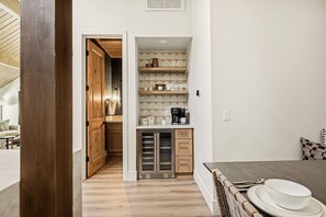 A compact kitchen with a microwave, coffee maker, and shelves with kitchenware. - Slope & Cedar House | Hot tub, Steps 2 Snow Summit (Big Bear Lake)