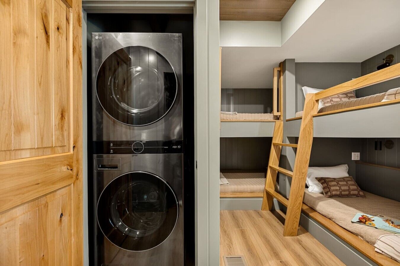 A compact room with a washing machine, bunk beds, and a wooden wardrobe.