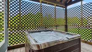 Una vasca idromassaggio in un'area esterna coperta con un muretto in legno e un recinto a griglia.