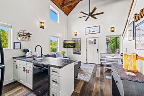 A modern kitchen with a large island, built-in appliances, and a ceiling fan. - Modern Tiny Home! Walk to Parkway*Hot Tub*Sleeps 6 (Pigeon Forge)