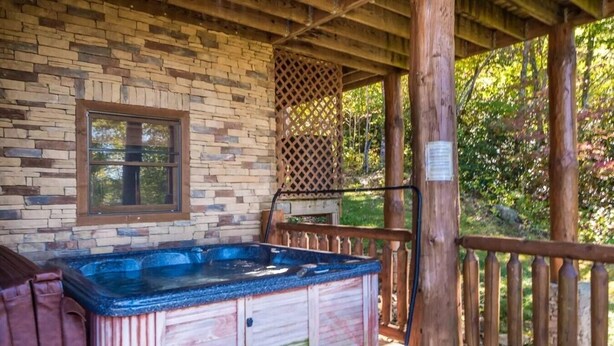 A hot tub with a wooden exterior, a window, and a wooden deck with a railing. - Peaceful 3BR*MTN Views*Hot Tub*Pool Table*Fire Pit (Sevierville)