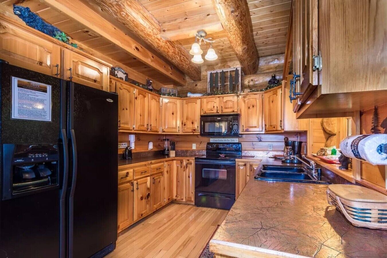 A kitchen with wooden cabinets, a black refrigerator, a microwave, and a stove.