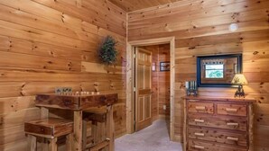A wooden interior with a wooden bench, a dresser, and a door leading to another room. - Peaceful 3BR*MTN Views*Hot Tub*Pool Table*Fire Pit (Sevierville)