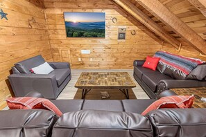 Ein Dachzimmer mit zwei Ledersofas, einem Holztisch und einem gerahmten Landschaftsbild.