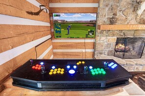 Ein Holzinnenraum mit einem Fernseher, der ein Golfspiel zeigt, einem Kamin und einem Billardtisch mit beleuchteten Knöpfen.