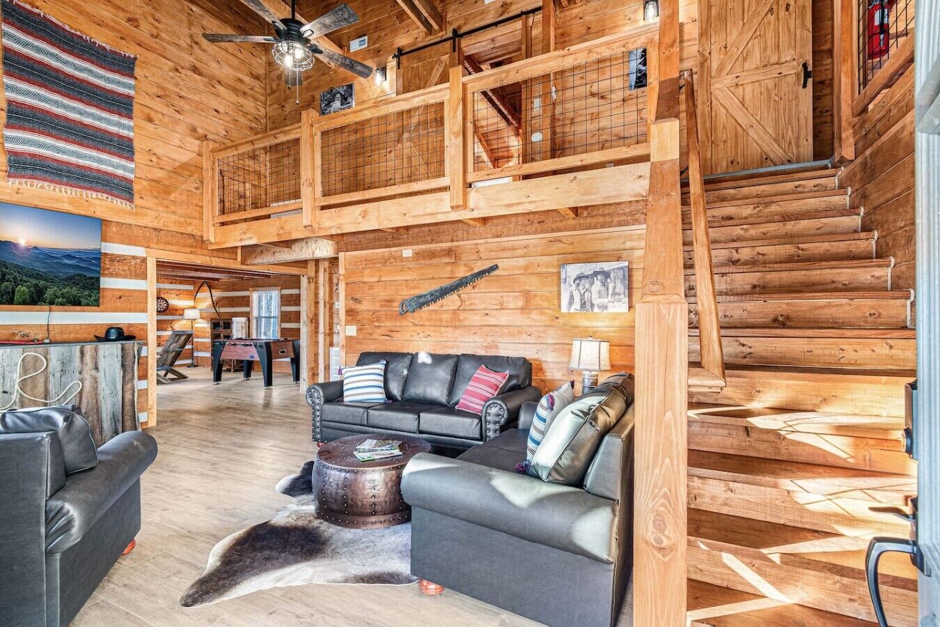 A log cabin interior with a high ceiling, a fireplace, a sofa set, and a dining area.