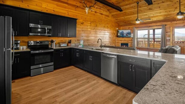 A modern kitchen with black cabinets, stainless steel appliances, and a wooden ceiling. - 5BR Pool Cabin w/MTN Views! Hot Tub*Games*Zipline! (Sevierville)