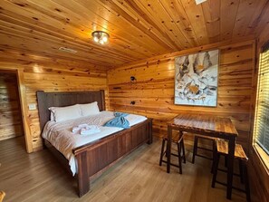 Une pièce dans une cabane en bois, avec un lit, une table et un tableau accroché au mur.