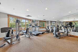 Un gimnasio con máquinas de cardio, máquinas de pesas y un espejo grande.