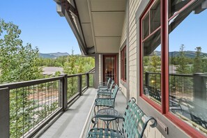 A balcony with a row of green metal chairs and a red door. - Beautiful Three-Bedroom Penthouse in Mountain Thunder Lodge (Breckenridge)