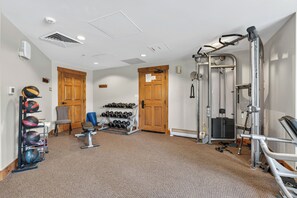 A gym with exercise equipment, a rack of dumbbells, and a door. - Beautiful Three-Bedroom Penthouse in Mountain Thunder Lodge (Breckenridge)