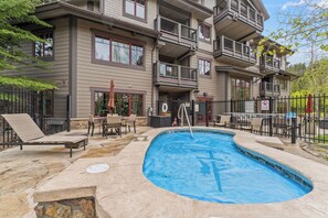 A multi-story building with a swimming pool, outdoor seating, and a fenced patio area. - Beautiful Three-Bedroom Penthouse in Mountain Thunder Lodge (Breckenridge)