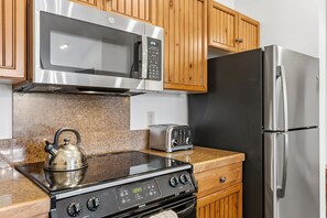 A kitchen with stainless steel appliances, including a microwave, oven, and refrigerator. - Beautiful Three-Bedroom Penthouse in Mountain Thunder Lodge (Breckenridge)