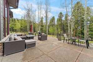 An outdoor patio with seating, a grill, and a view of a forest. - Beautiful Three-Bedroom Penthouse in Mountain Thunder Lodge (Breckenridge)