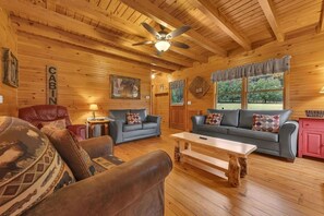 A cabin interior with a wooden ceiling, two sofas, a coffee table, and a ceiling fan. - Creekside 3BR w/Fire Pit and Hot Tub! Peaceful! (Cosby)