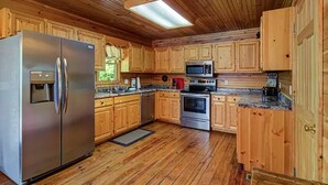 Eine moderne Küche mit Holzschränken, Edelstahlgeräten und Holzboden.