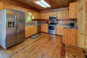 Eine moderne Küche mit Holzschränken, Edelstahlgeräten und Holzboden.