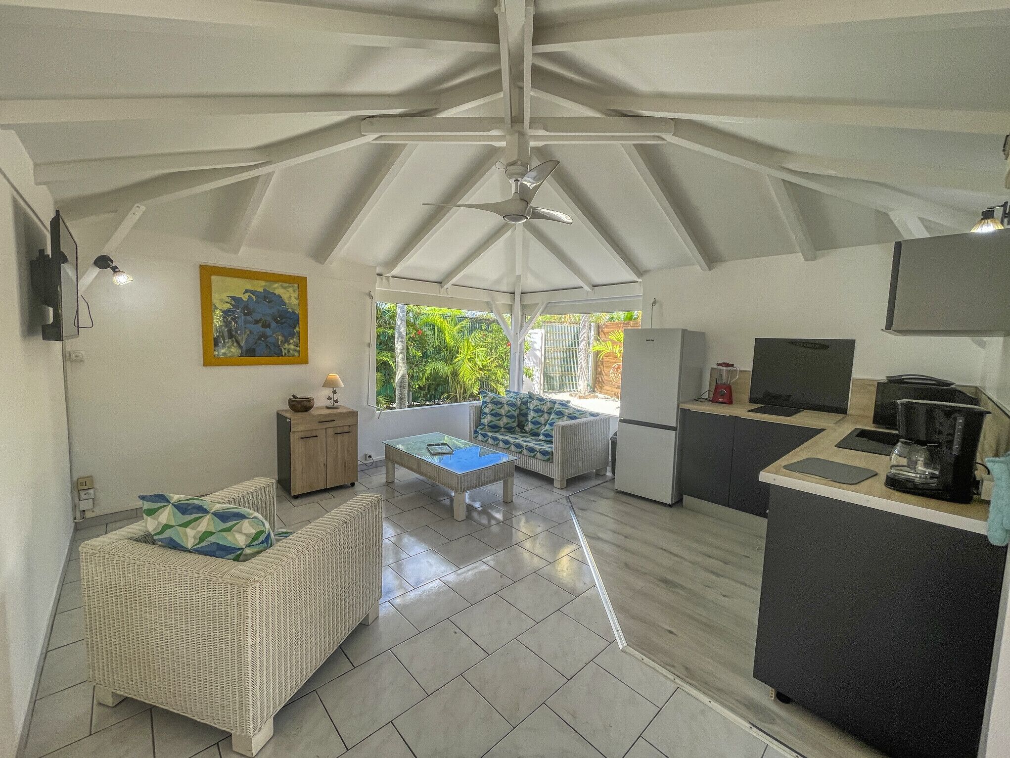 A compact kitchen with a dining area, a refrigerator, a coffee maker, and a television.
