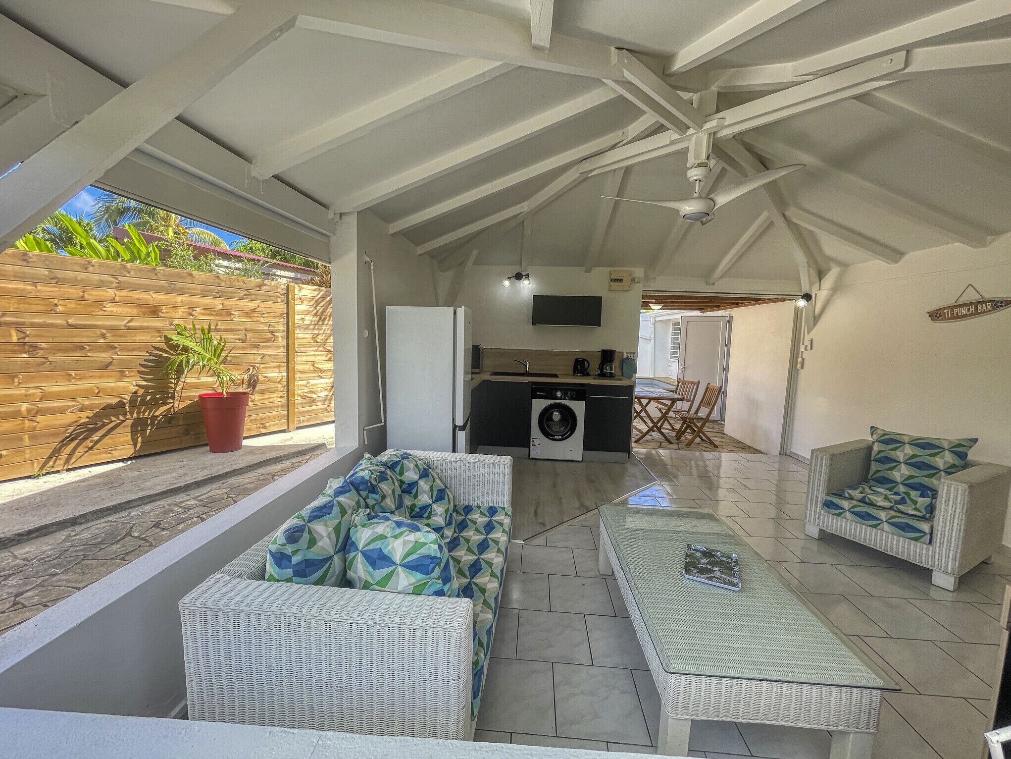 A covered outdoor area with a kitchen, seating, and a view of the outside.