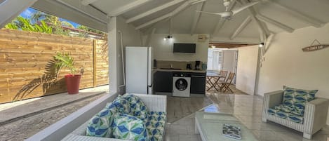 A covered outdoor area with a kitchen, seating, and a view of the outside.